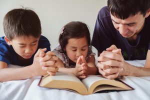 parent and children praying on the bed, family pray together